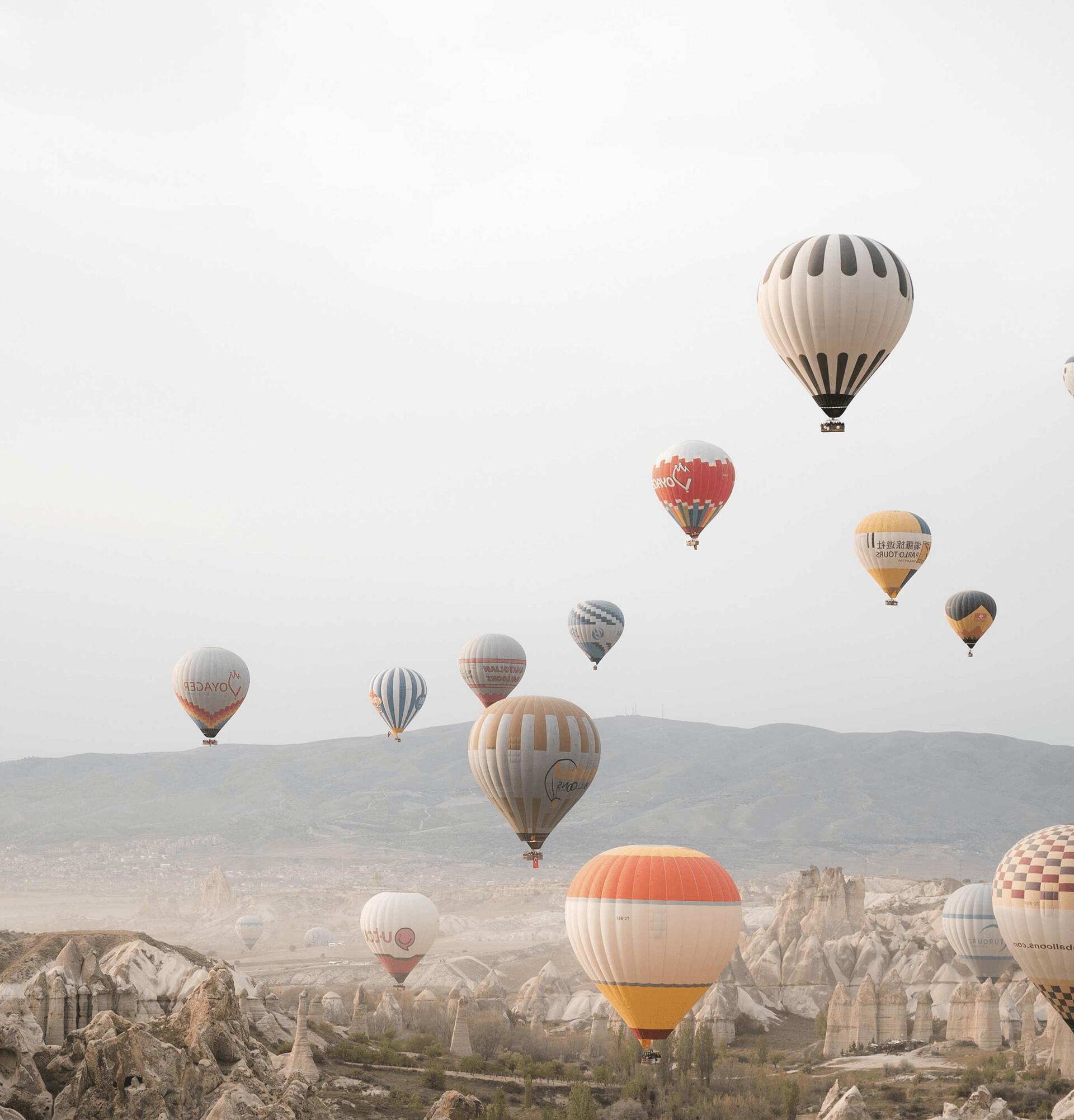 Hot air balloons drift through the sky over the otherworldly terrain of Cappadocia.